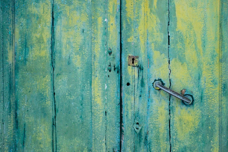 a bright green painted door with a rusty handle