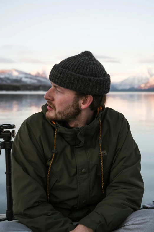 a man sitting on top of a boat next to a body of water