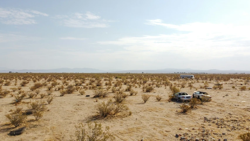 an open, sandy area with a van in the distance