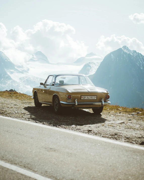 an old brown car sitting on the side of the road