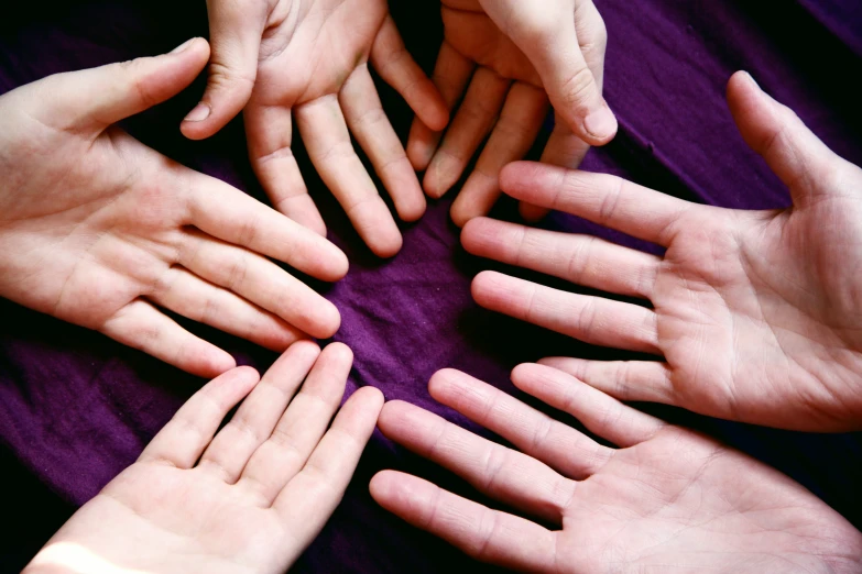 a group of hands stacked into the center of a circle