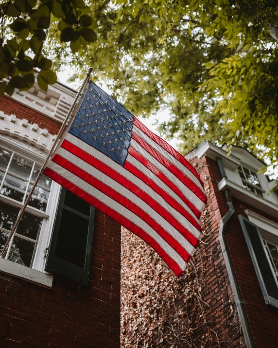 an american flag hangs on a building in front of it