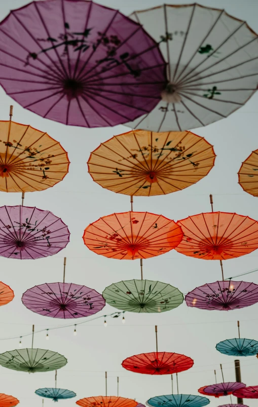 multicolored umbrellas hang from a ceiling in a room