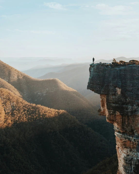 a man standing on top of a cliff overlooking a valley