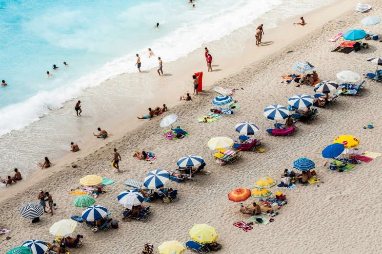 a beach with many umbrellas and a lot of people standing around it