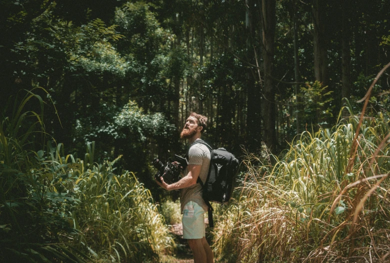 a man is standing in the woods with a backpack