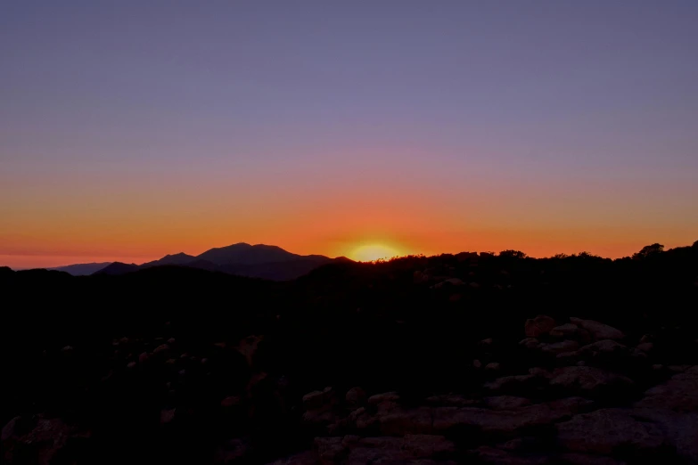 the setting sun in the distance, with dark mountains in the background