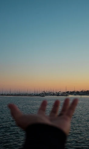 the hand has raised up above the water to catch the sunset
