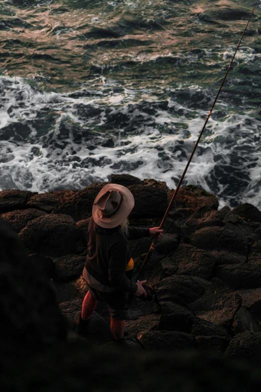 a man is fishing on a rocky coast with a fishing rod