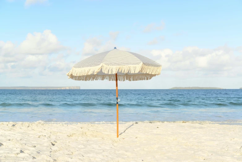 a umbrella on a beach with the ocean in the background