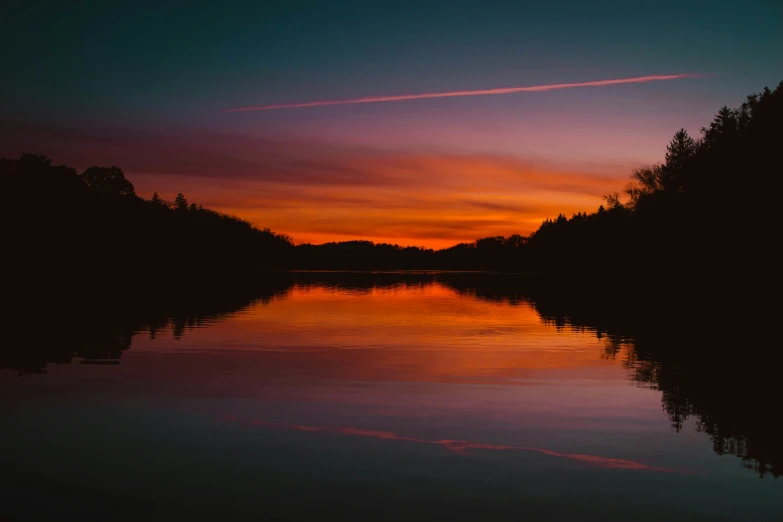 the sunset reflecting off the water of a lake