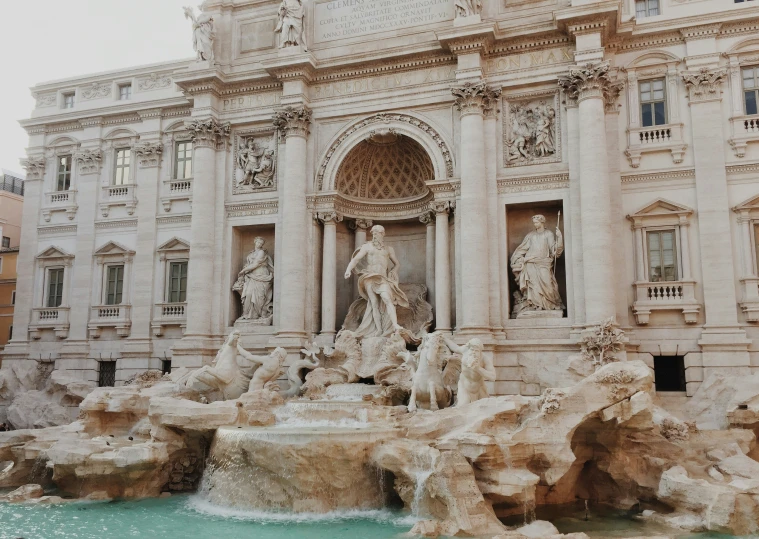 the water fountain has statues on it by the building