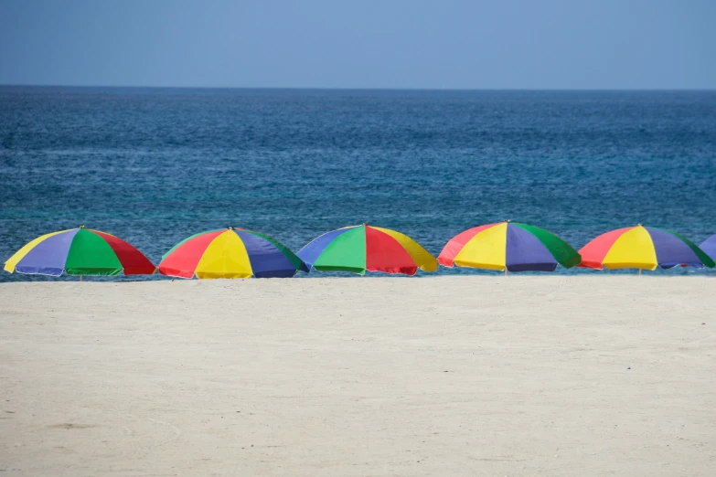 colorful beach umbrellas are lined up on a sandy shore