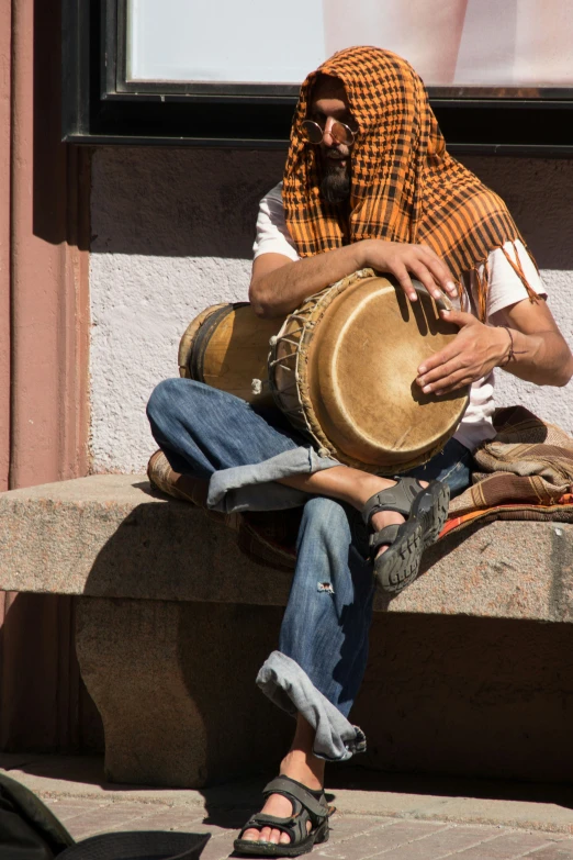 man sitting down with a hat and blanket