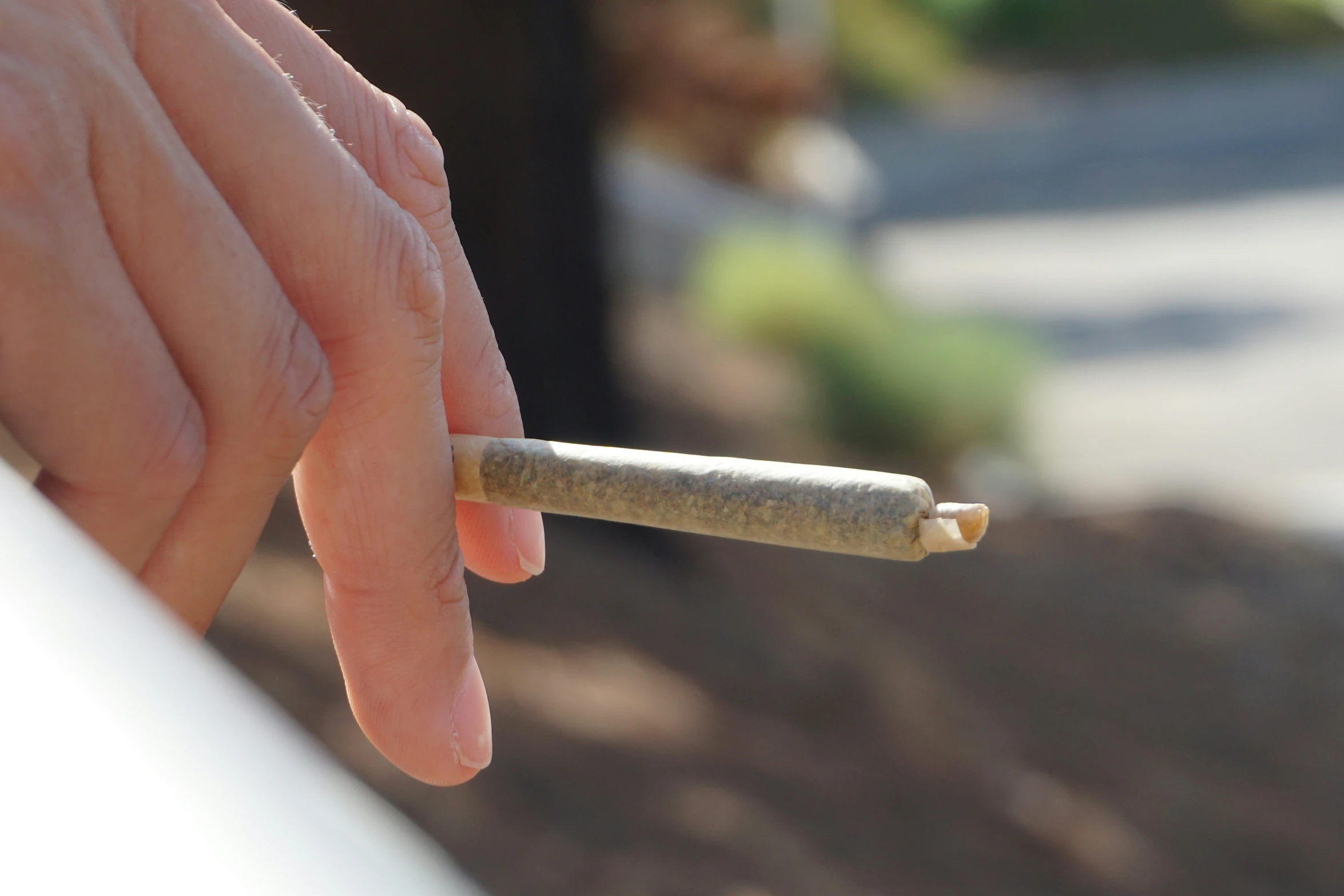 a hand holding a small cigarette with no ash on it