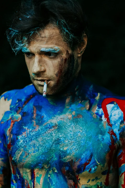 man with painted face and shirt is smoking a cigarette