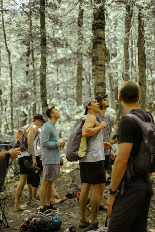 group of men hiking in a forest with many backpacks