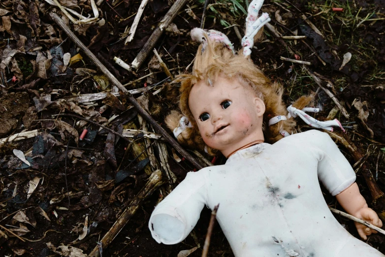an old doll is laying on the ground in the woods