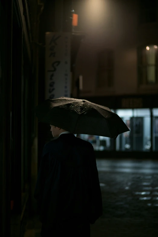 man walking down an alley with umbrella at night