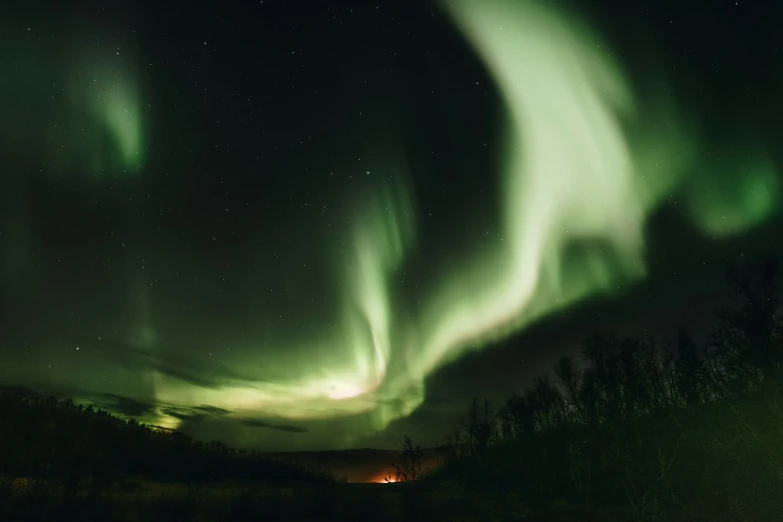 an image of green and white aurora lights in the night sky