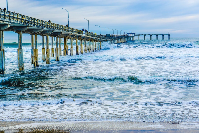 a pier on the beach with waves coming in