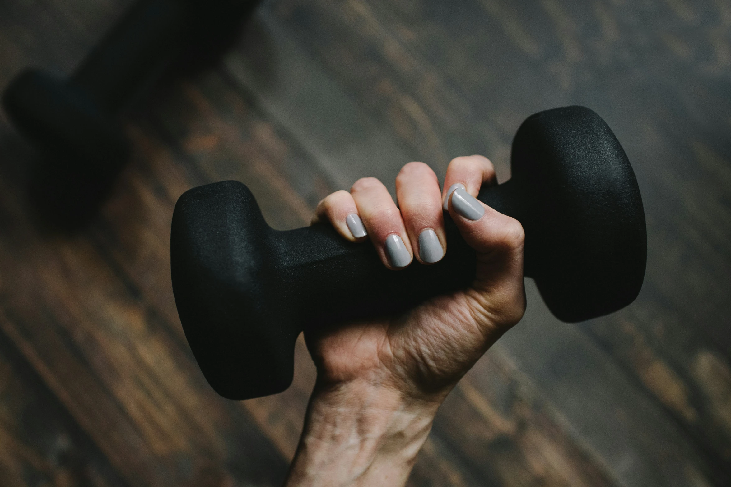 the dumb presses a black dumbbell against a wooden background