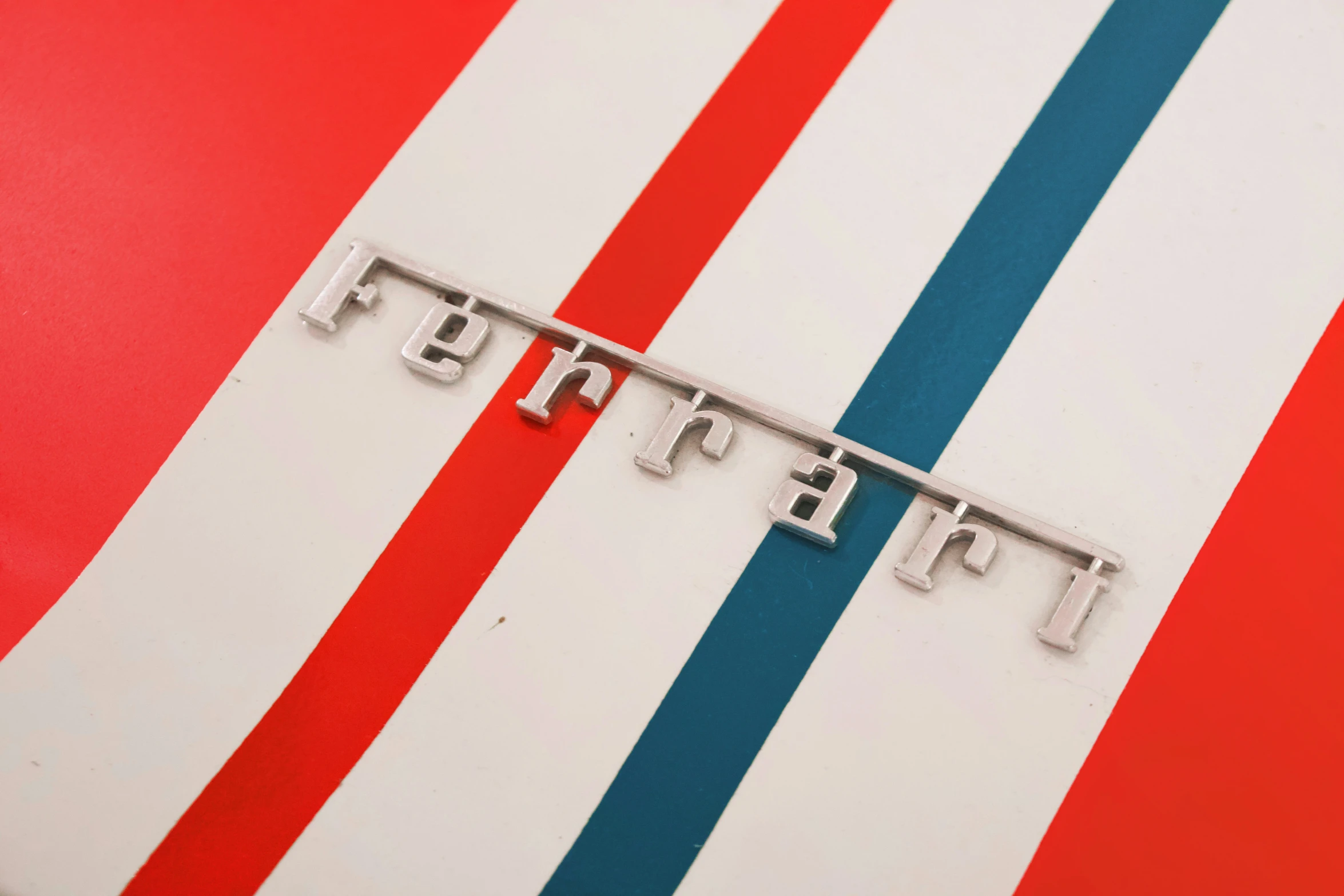 a car engine hood emblem sits on a red and white car