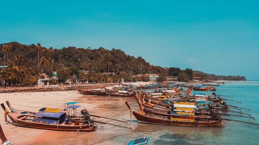 long boats are docked on the beach next to the water