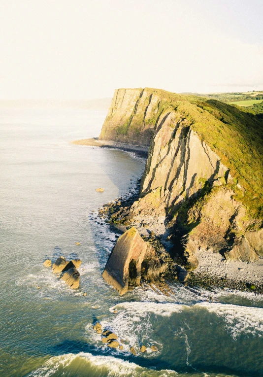 a view of the ocean with green cliffs and water