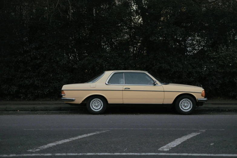 an old yellow car is parked by a tree