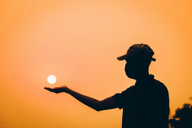 a man holding up a ball on a sunny sky