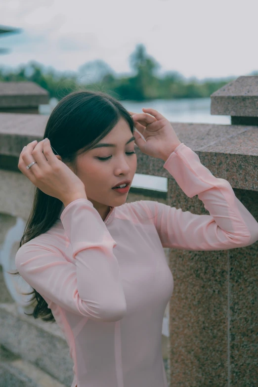 an asian woman holds her hand behind her head