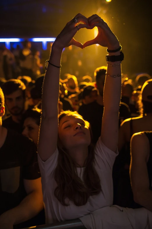 a woman in a crowd is making a heart sign