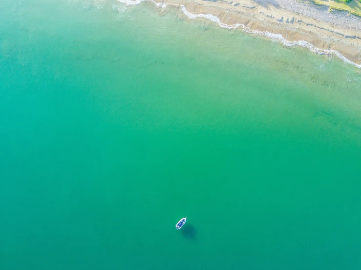 the water looks very blue, with a small white boat