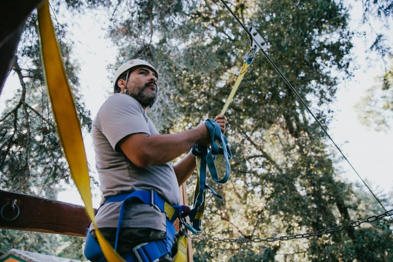 man climbing high on a rope course in the forest