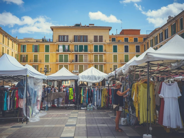 a very long sidewalk with several tents and cloths for sale