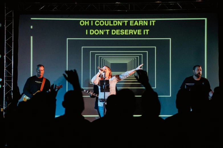 a person singing at an event, with a picture in the background that reads oh i couldn't earn it don't observe it