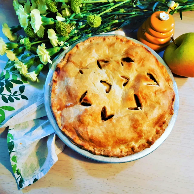 an apple pie sitting next to some flowers