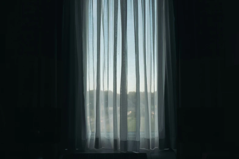 a window with sheer curtains and a tv