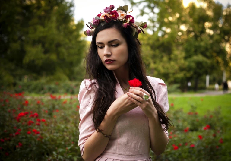 a woman in a pink dress holding a red flower