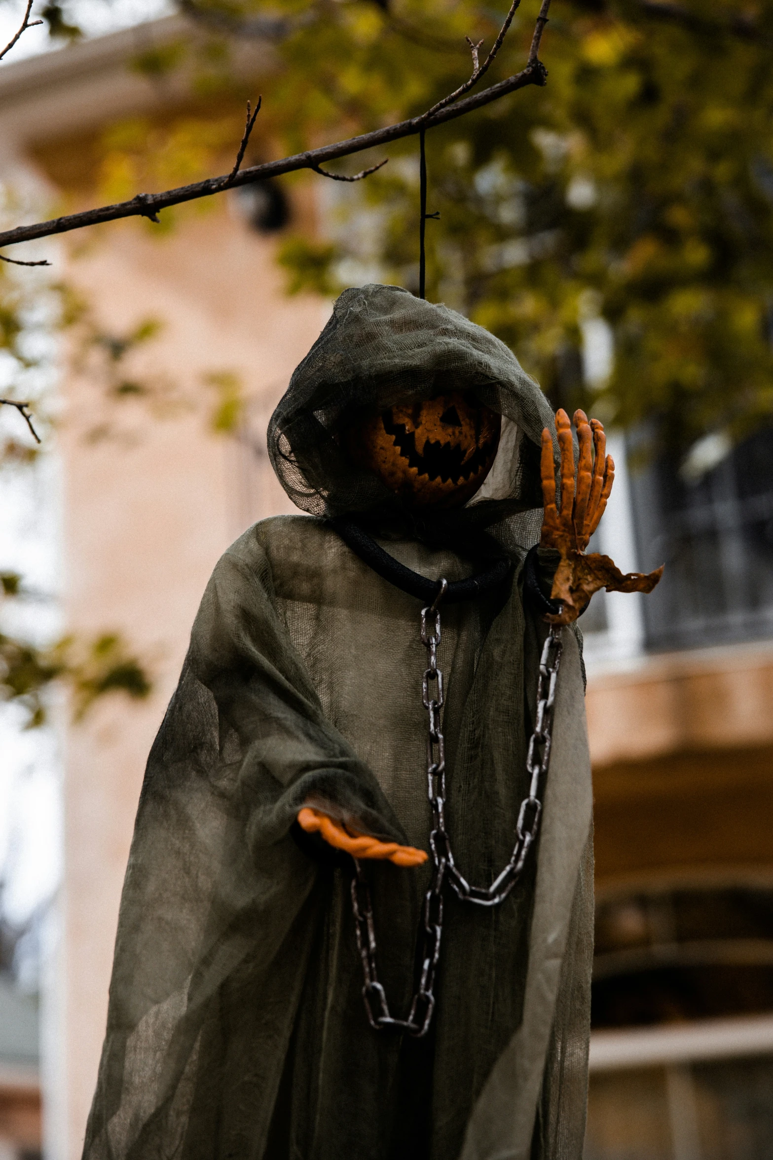 a scarecrow hanging from a tree holding a chain