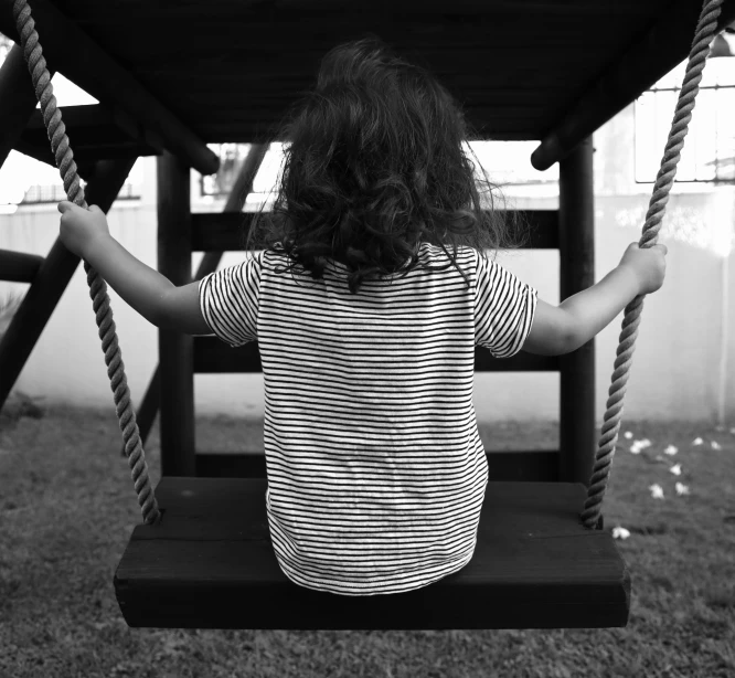 black and white pograph of  sitting on swing