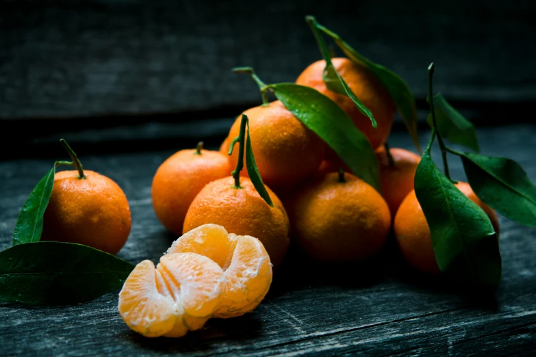 several whole and cut oranges on a table