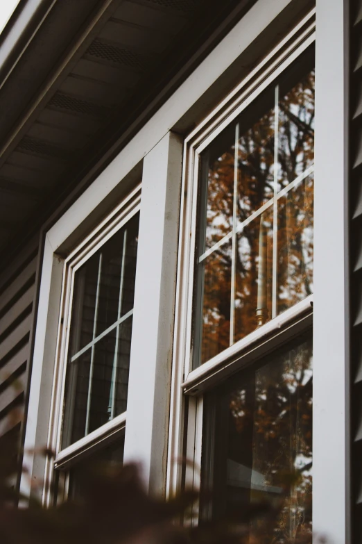 a view through two windows to autumn leaves in the background