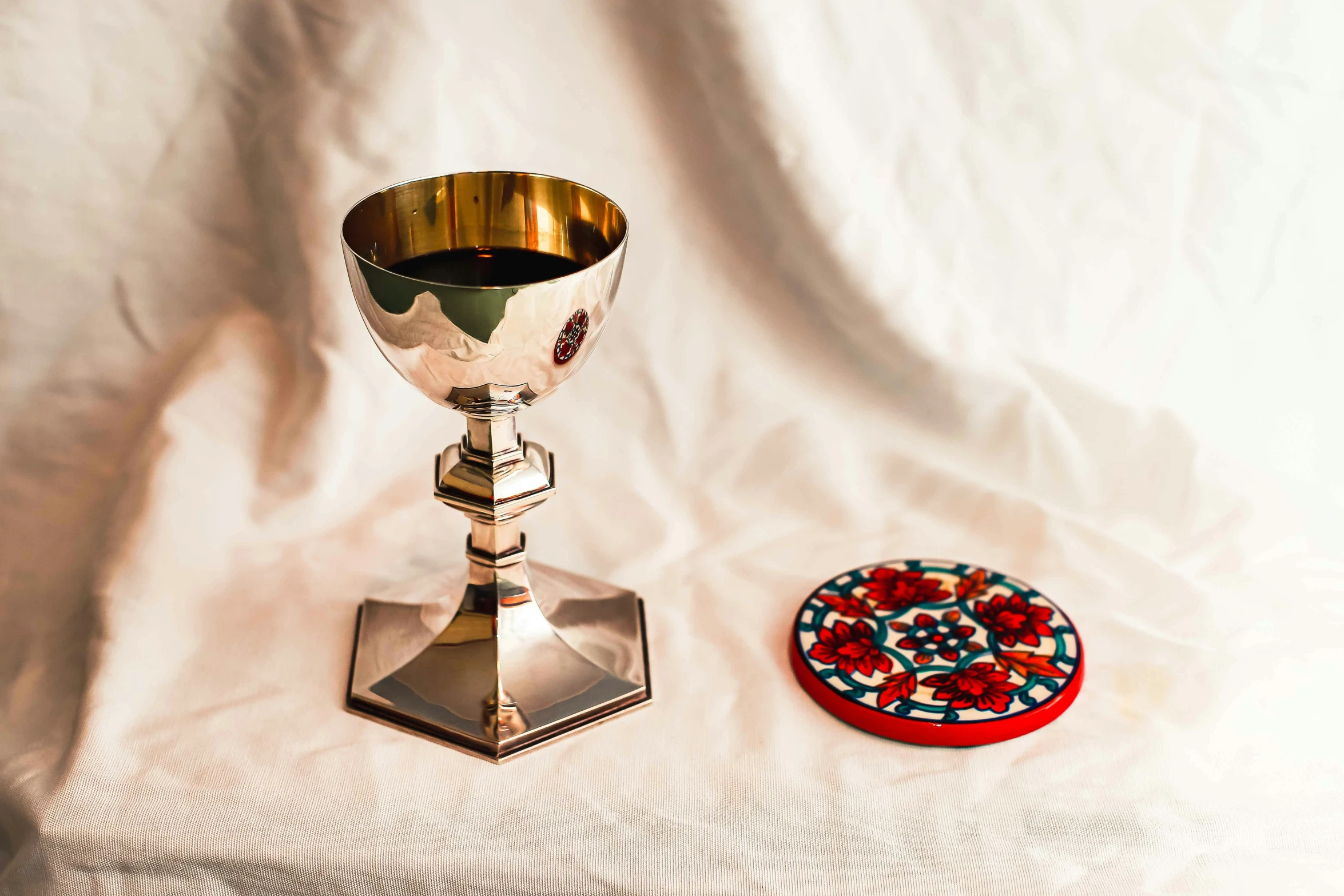 a small plate and a small pew cup on a white cloth