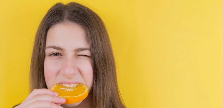 a woman biting into an orange with her mouth