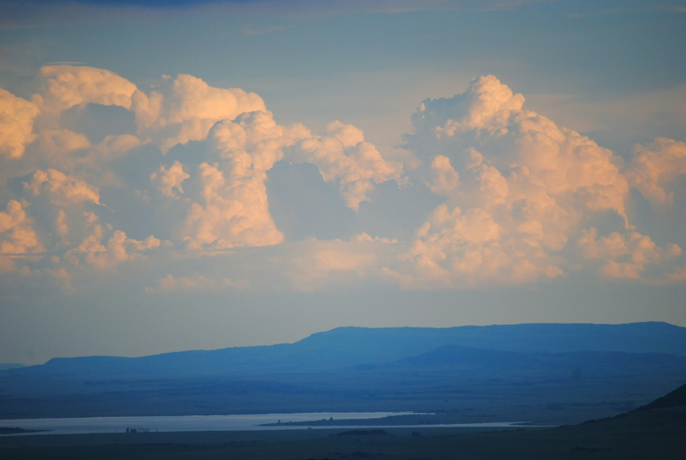 large cloud over mountains with small lake in the middle