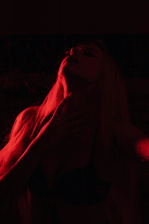 a woman sitting in the dark and her hair blowing