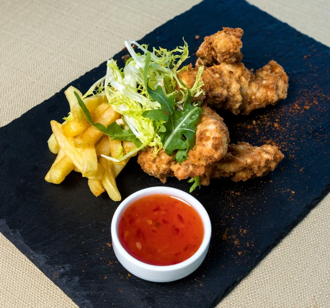 some fried chicken sitting on a plate next to vegetables