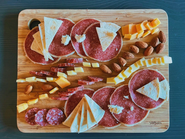 various food on a  board including ham, cheese, and fruits